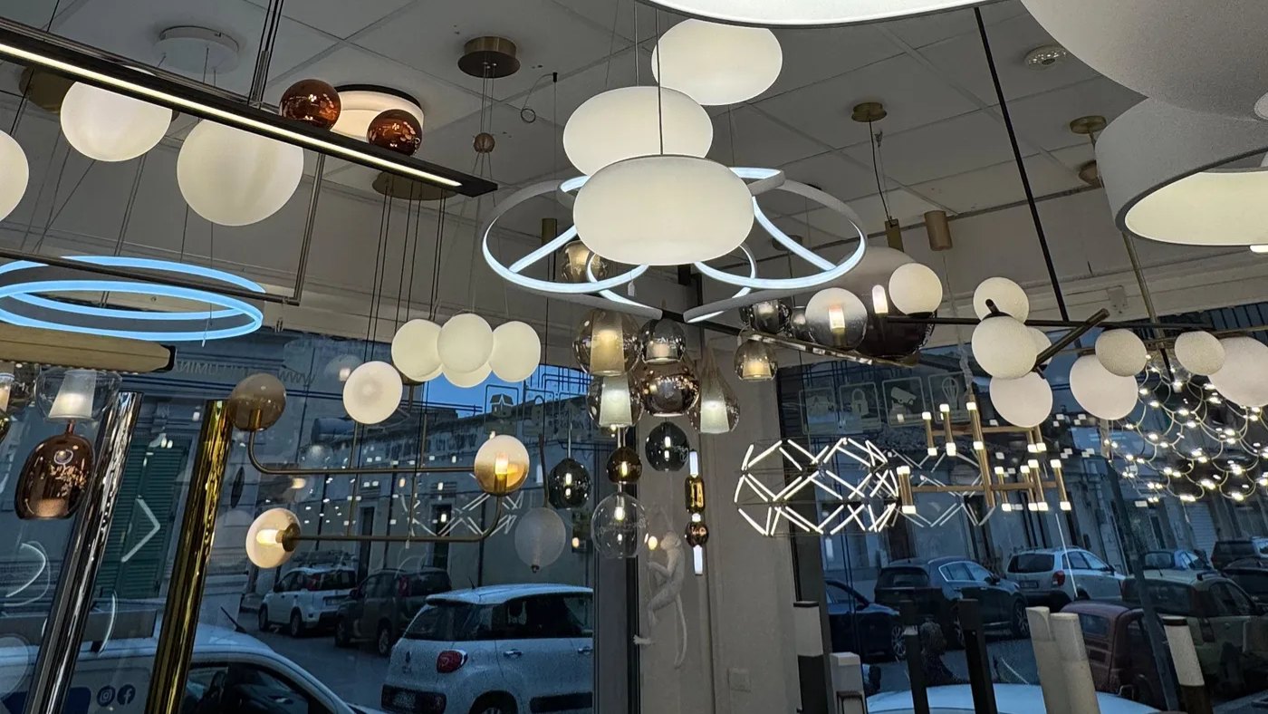 Vetrina dello showroom Area Illumina con l’insegna e le lampade accese