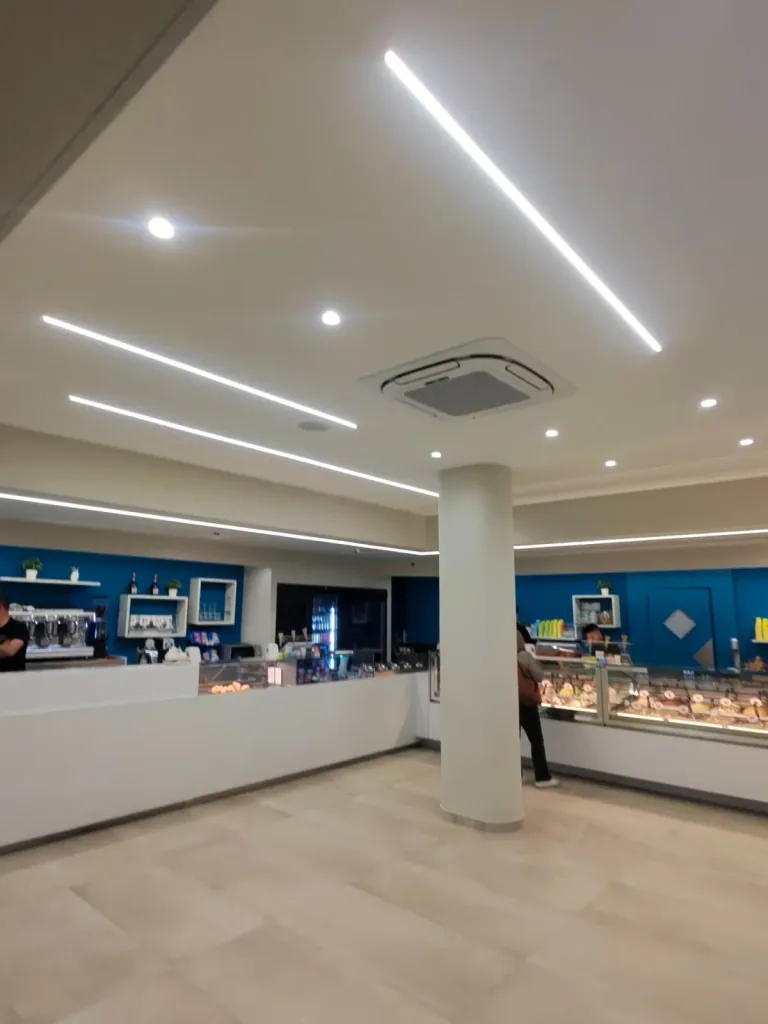 Sala del Bar Riviera con tagli di luce LED lineari nel soffitto e il banco gelati