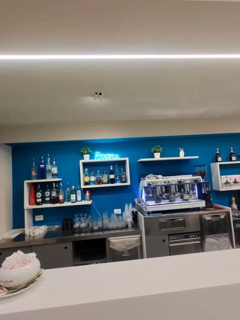 Parete blu con mensole e bottiglie sopra la macchina del caffè