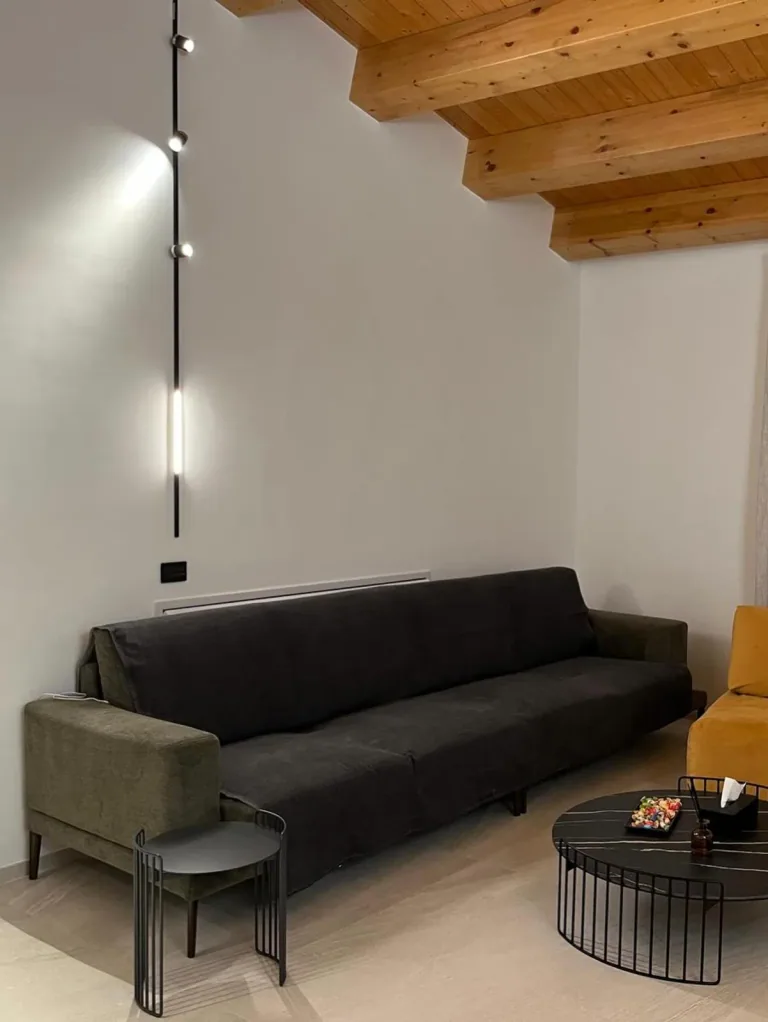 Divano sotto le sospensioni lineari che scendono dal soffitto in legno