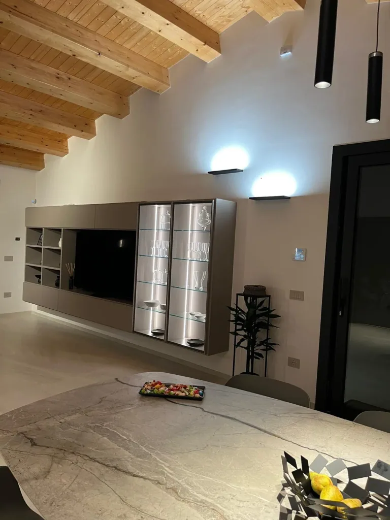 Parete attrezzata con vetrine illuminate e applique sopra il tavolo