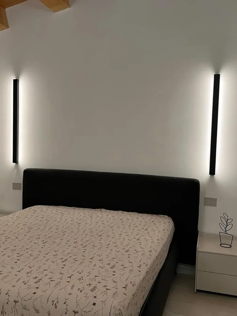 Camera con due barre LED verticali ai lati del letto