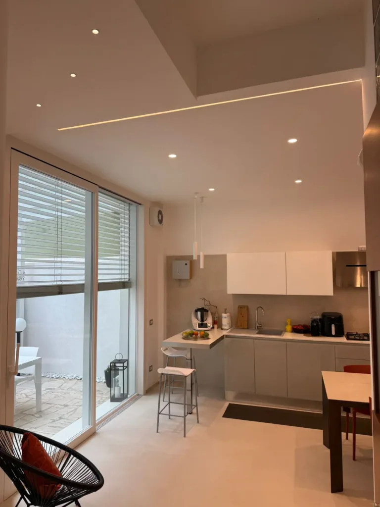 Cucina e zona pranzo con un taglio di luce LED nel soffitto e faretti a incasso
