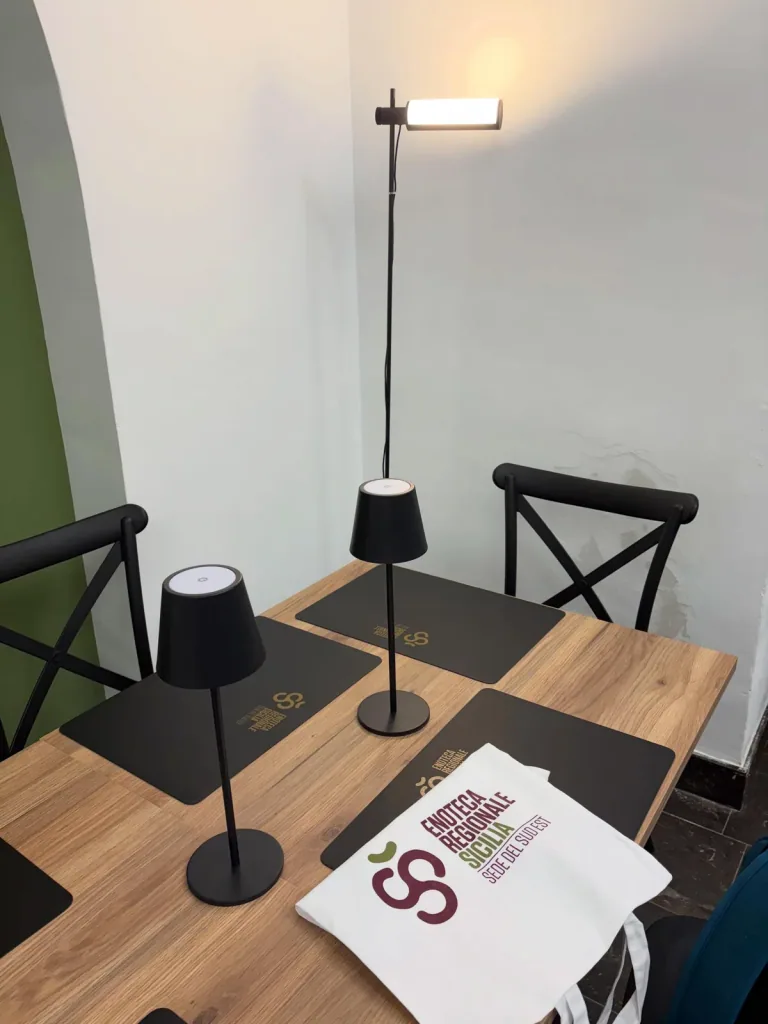 Tavolo di degustazione dell’Enoteca Regionale con lampade da tavolo e una lampada da terra accese