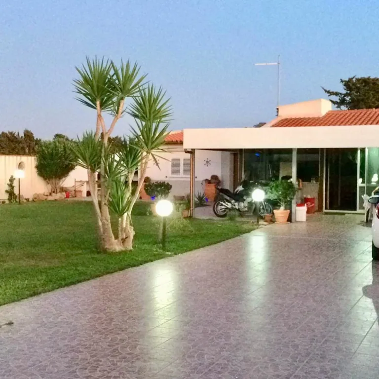 Viale d’ingresso di una casa con paletti luminosi a sfera accesi al tramonto