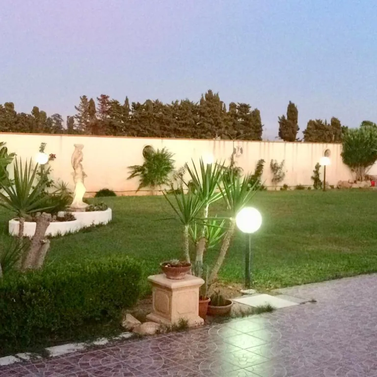 Paletti a sfera accesi tra le palme del giardino