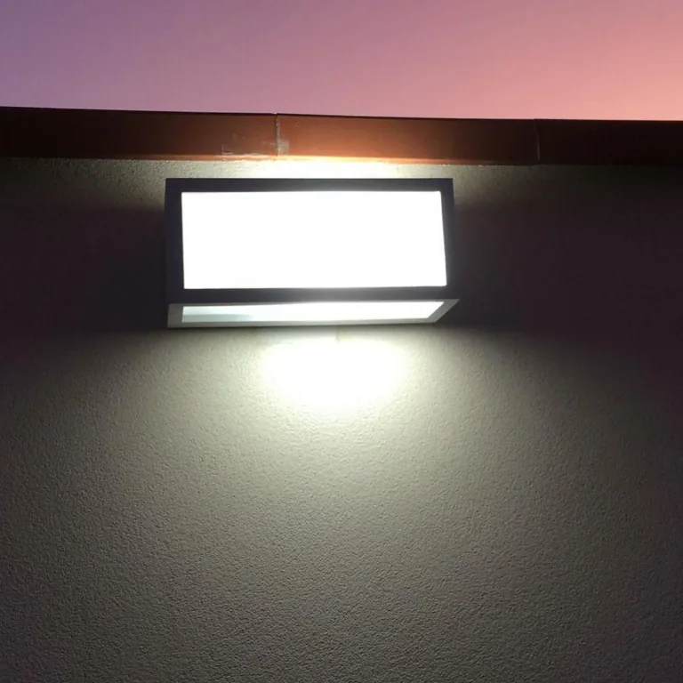 Applique da esterno rettangolare accesa sul muro al crepuscolo