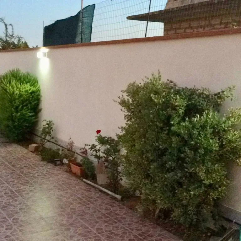 Muro di cinta con applique accese sopra le aiuole