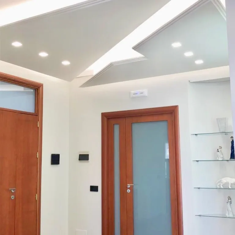 Soffitto con profili LED incassati e applique a parete
