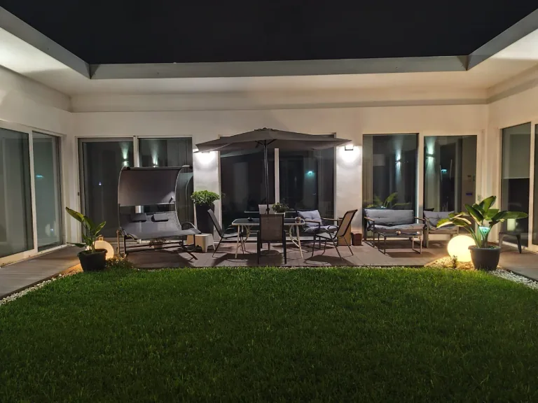 Il patio visto dal prato con le luci accese sotto il porticato