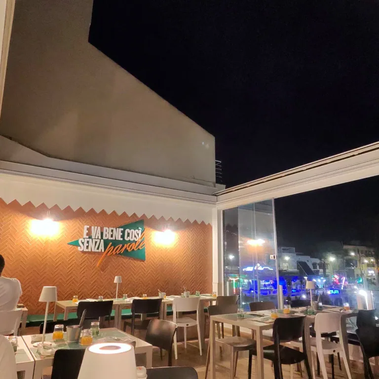 Terrazza della pizzeria di sera con applique accese sulla parete arancione